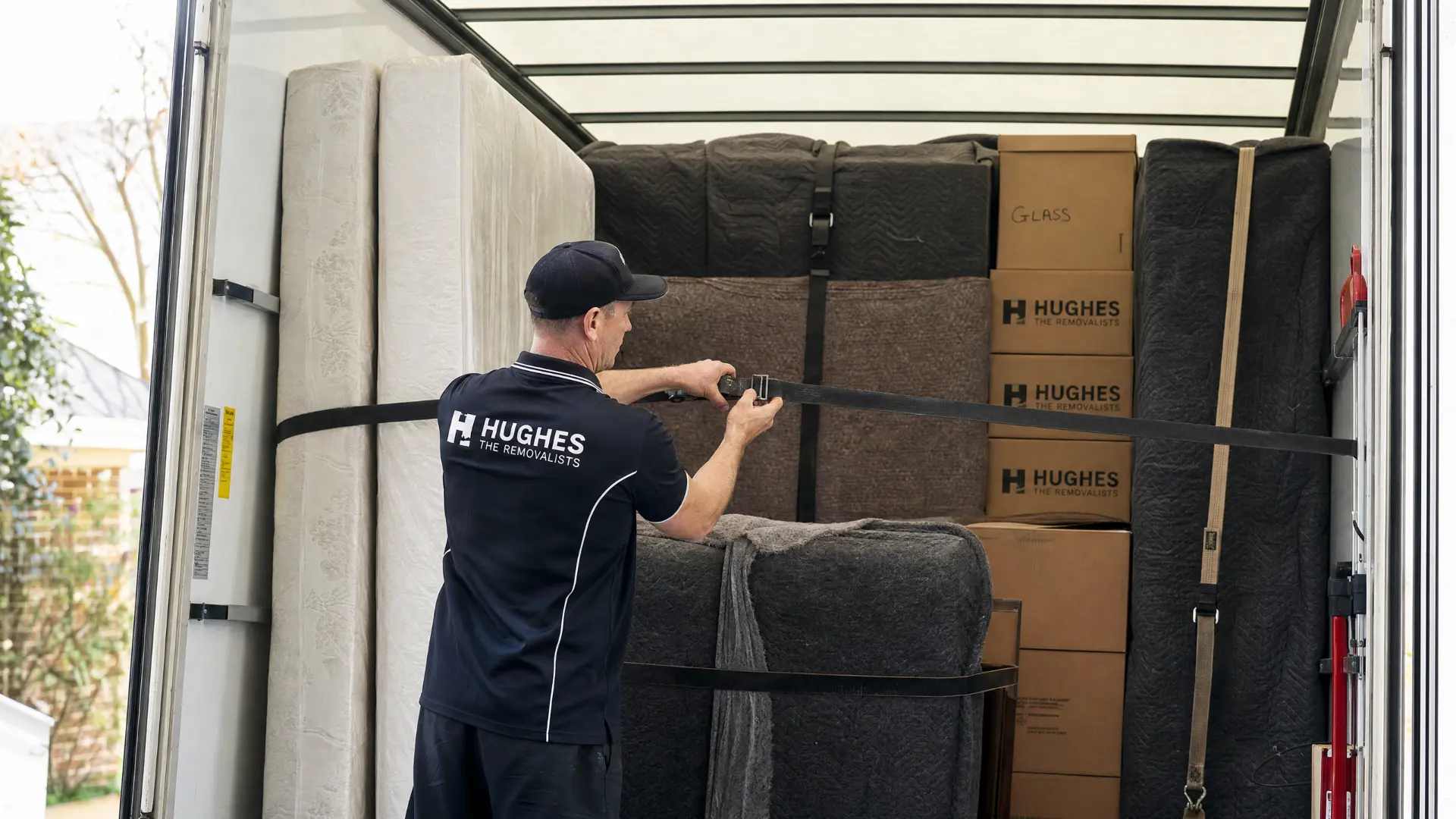 Removalist strapping furniture and boxes inside a moving truck